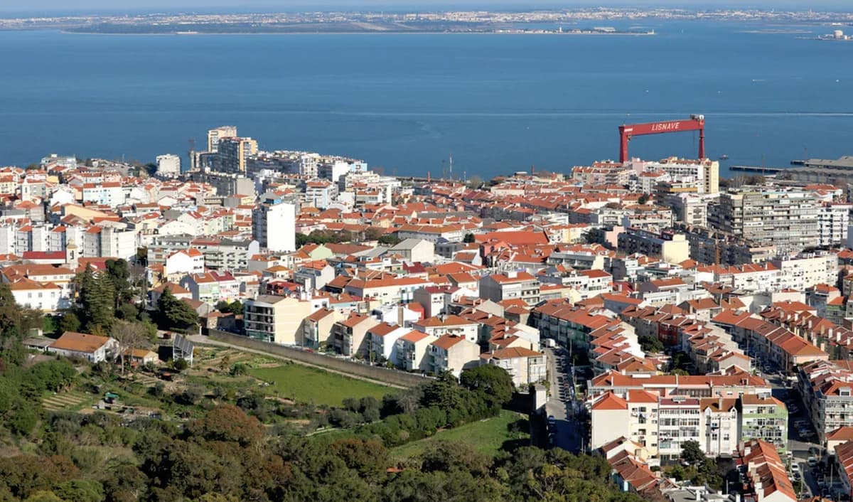 Vista panorâmica de Almada com edifícios residenciais e o Tejo ao fundo.
